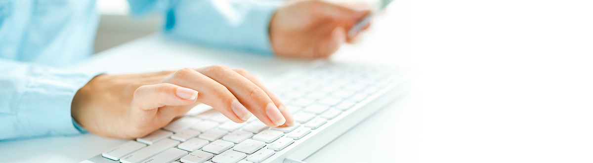 Person typing on a keyboard while looking at credit card. 